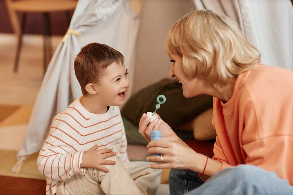 mother playing with disabled young son, with bubbles