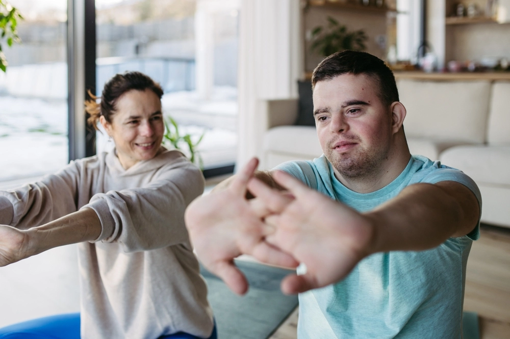 caretaker and disabled men doing yoga and stretching together